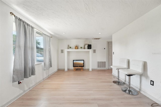 living area with light wood-style flooring, baseboards, and a fireplace