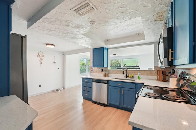 kitchen featuring blue cabinetry, tasteful backsplash, stainless steel appliances, and a sink