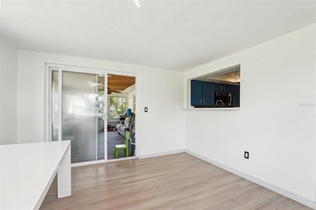 unfurnished dining area with light wood finished floors, baseboards, and a ceiling fan