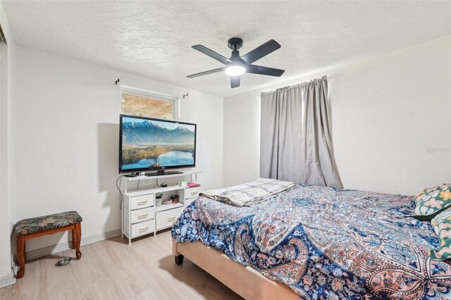 bedroom featuring light wood-style flooring, a ceiling fan, and baseboards