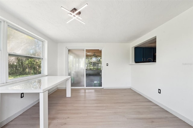 interior space featuring baseboards, a textured ceiling, and light wood-type flooring