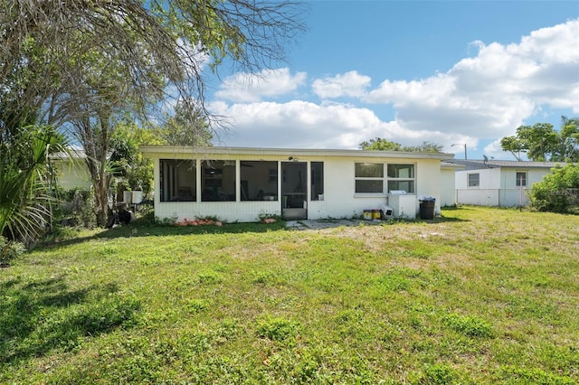 rear view of property with fence, a lawn, and a sunroom