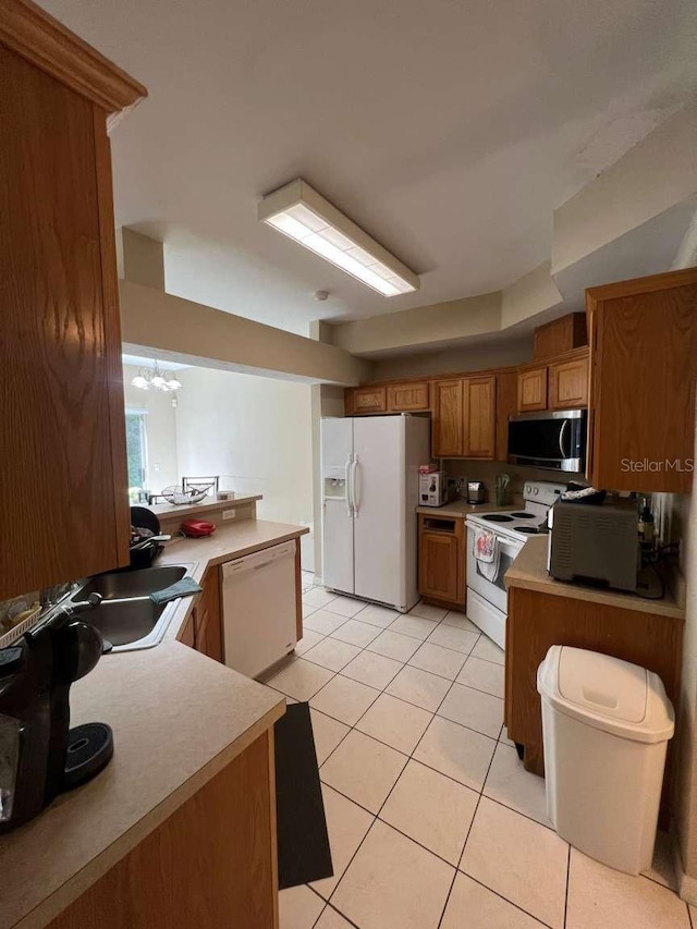 554 NW 50th Blvd, Gainesville, FL 32607 - kitchen featuring light tile patterned floors, light countertops, brown cabinetry, and white appliances