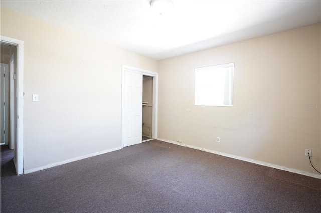 unfurnished bedroom with dark colored carpet, baseboards, and a closet