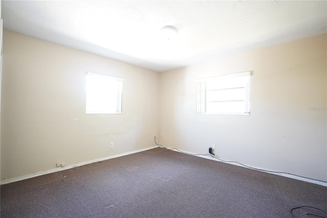 unfurnished room with dark colored carpet and baseboards