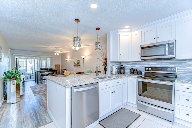 13870 Oakwood Ln Unit 13870, Seminole, FL 33776 - kitchen featuring stainless steel appliances, a peninsula, a sink, a textured ceiling, and ceiling fan