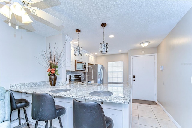 13870 Oakwood Ln Unit 13870, Seminole, FL 33776 - kitchen featuring white cabinets, appliances with stainless steel finishes, a breakfast bar area, and a peninsula