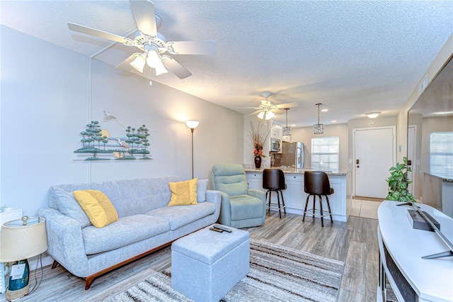 13870 Oakwood Ln Unit 13870, Seminole, FL 33776 - living room featuring light wood-type flooring, a ceiling fan, and a textured ceiling