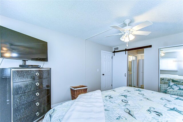 13870 Oakwood Ln Unit 13870, Seminole, FL 33776 - bedroom with a barn door, a textured ceiling, a ceiling fan, and visible vents