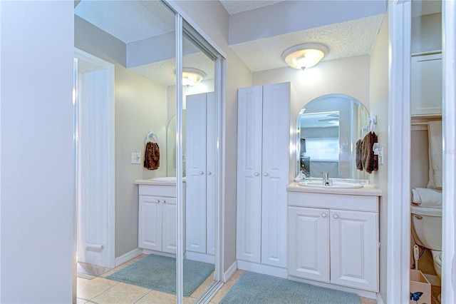 13870 Oakwood Ln Unit 13870, Seminole, FL 33776 - bathroom with tile patterned floors, a textured ceiling, a closet, vanity, and toilet