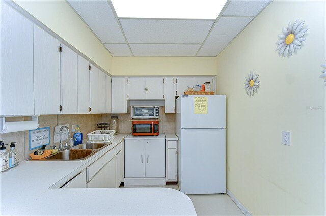 13870 Oakwood Ln Unit 13870, Seminole, FL 33776 - kitchen featuring a drop ceiling, backsplash, a sink, stainless steel microwave, and freestanding refrigerator