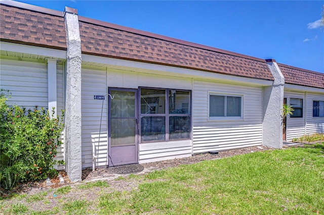 13870 Oakwood Ln Unit 13870, Seminole, FL 33776 - rear view of property featuring a yard, roof with shingles, and mansard roof