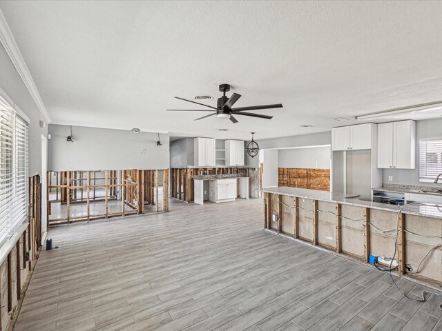 kitchen with a ceiling fan, light stone counters, light wood-style flooring, white cabinetry, and freestanding refrigerator
