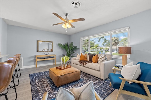living room featuring ceiling fan, baseboards, wood finished floors, and visible vents