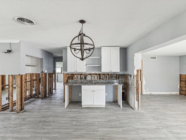 kitchen with open shelves, visible vents, white cabinetry, and a notable chandelier