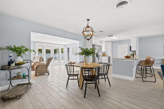 dining room featuring light wood-style floors, visible vents, baseboards, and an inviting chandelier