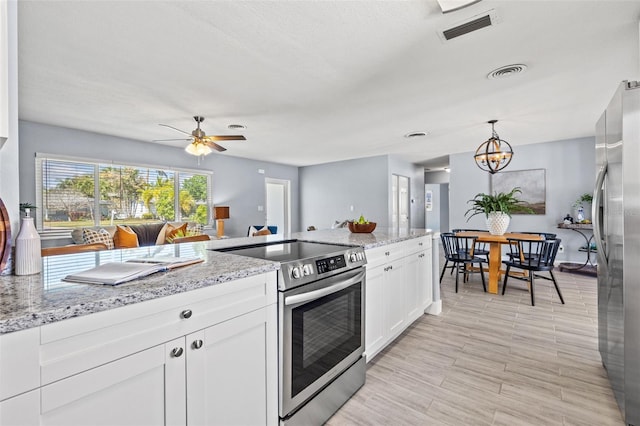 kitchen featuring white cabinets, appliances with stainless steel finishes, light stone counters, and visible vents