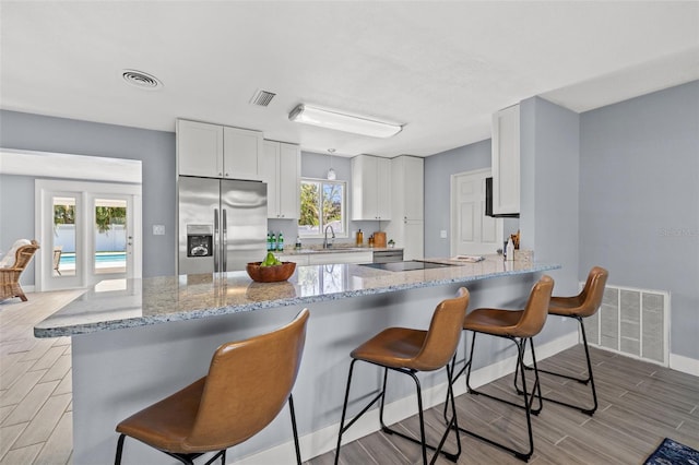 kitchen featuring light wood-type flooring, stainless steel refrigerator with ice dispenser, visible vents, and a sink