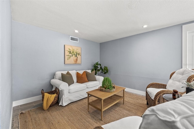 living area featuring recessed lighting, a textured ceiling, visible vents, and baseboards