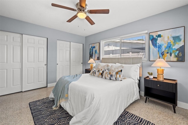 bedroom with speckled floor, two closets, a ceiling fan, and baseboards