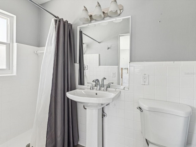 full bathroom featuring tile walls, wainscoting, a shower stall, and toilet
