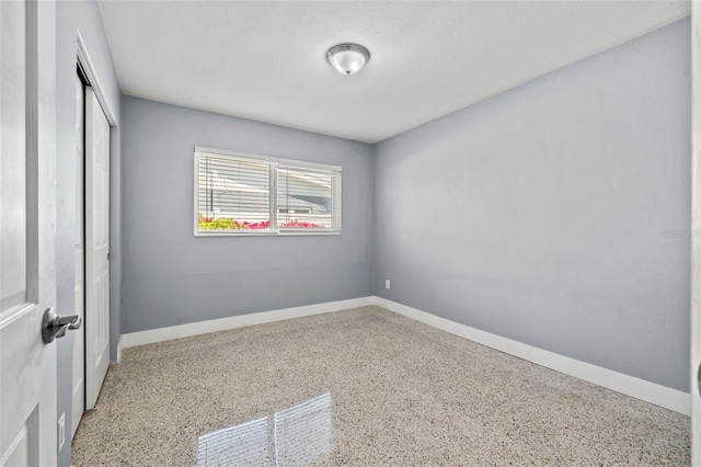 unfurnished bedroom with baseboards, speckled floor, and a closet