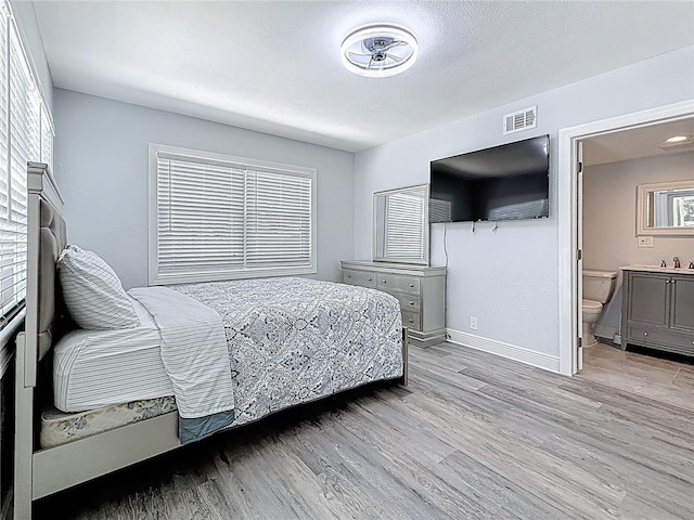 6609 Dartmouth Ave N, Saint Petersburg, FL 33710 - bedroom featuring a sink, light wood finished floors, baseboards, ensuite bath, and visible vents