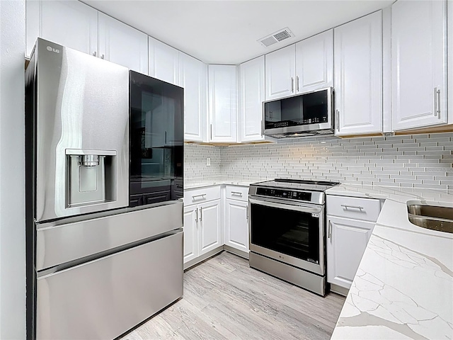 6609 Dartmouth Ave N, Saint Petersburg, FL 33710 - kitchen featuring white cabinetry, stainless steel appliances, visible vents, and light wood-type flooring