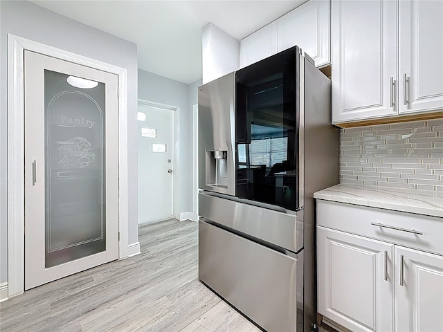 6609 Dartmouth Ave N, Saint Petersburg, FL 33710 - kitchen with light stone counters, decorative backsplash, stainless steel fridge with ice dispenser, light wood finished floors, and white cabinets