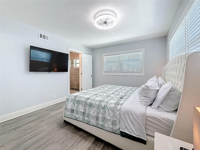 6609 Dartmouth Ave N, Saint Petersburg, FL 33710 - bedroom featuring wood finished floors, visible vents, connected bathroom, baseboards, and a textured ceiling