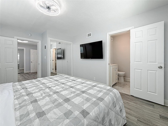 6609 Dartmouth Ave N, Saint Petersburg, FL 33710 - bedroom with a textured ceiling, wood finished floors, a closet, connected bathroom, and visible vents