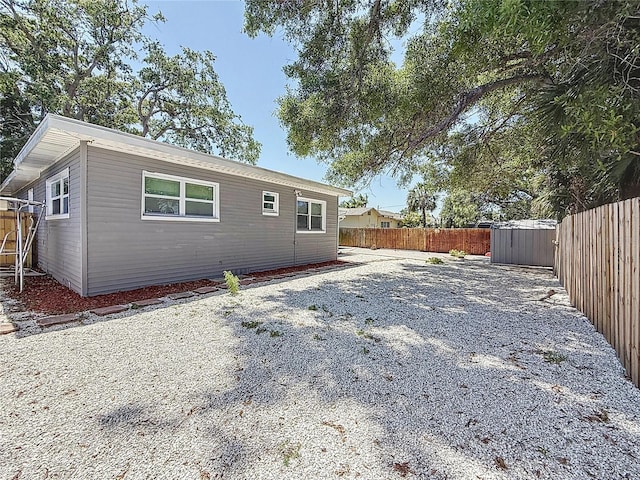 6609 Dartmouth Ave N, Saint Petersburg, FL 33710 - back of house with a storage unit, an outbuilding, and a fenced backyard