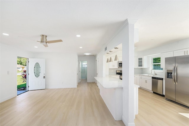 kitchen with stainless steel appliances, a sink, light wood-style floors, white cabinetry, and recessed lighting