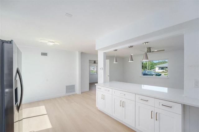 kitchen with stainless steel refrigerator with ice dispenser, white cabinetry, light wood-style flooring, a peninsula, and light stone countertops