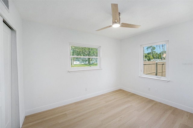 unfurnished room featuring light wood finished floors, healthy amount of natural light, a ceiling fan, and baseboards