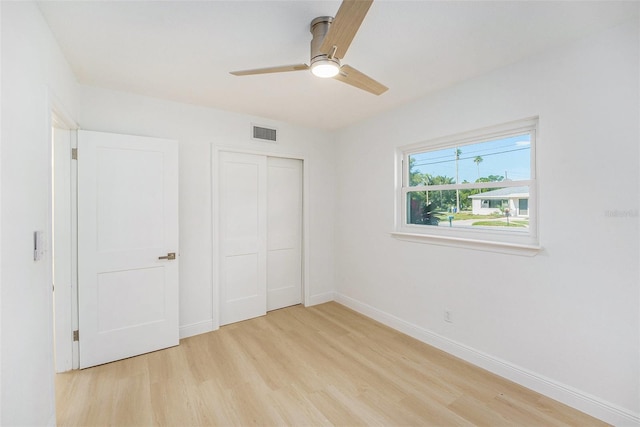 unfurnished bedroom featuring light wood-type flooring, a closet, baseboards, and ceiling fan