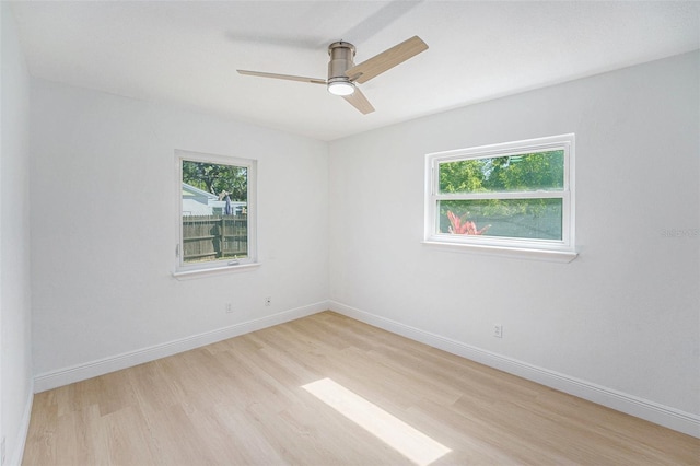 empty room featuring light wood-type flooring, a ceiling fan, and baseboards