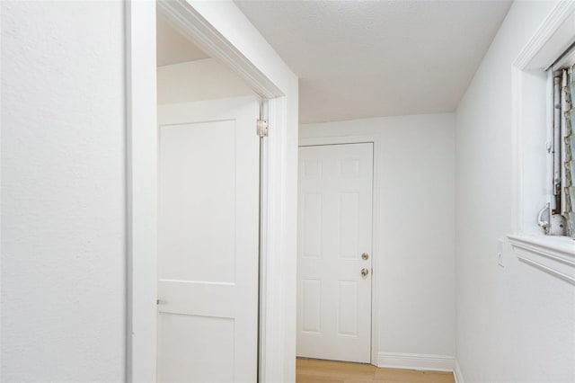 hall featuring light wood-style flooring and baseboards