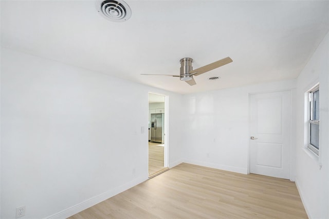 empty room with light wood-type flooring, a ceiling fan, and baseboards