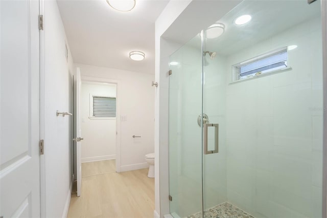 full bath featuring toilet, a shower stall, wood finished floors, and baseboards