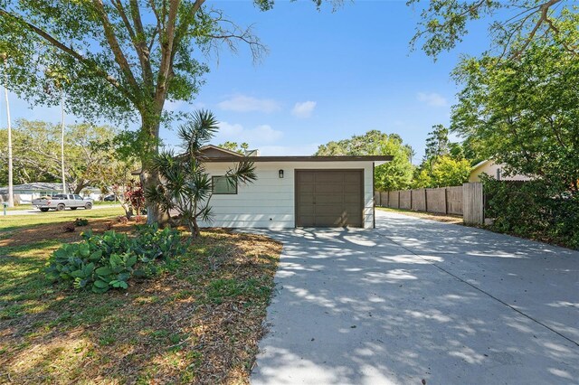 view of property exterior featuring fence, driveway, and an attached garage