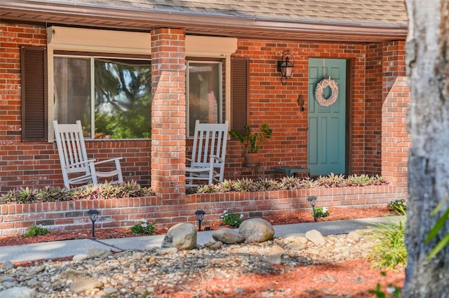 19254 Blount Rd, Lutz, FL 33558 - property entrance featuring brick siding, a shingled roof, and covered porch