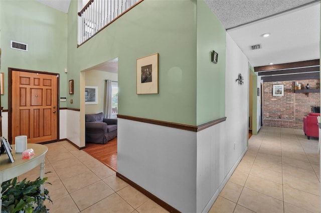 19254 Blount Rd, Lutz, FL 33558 - hall featuring light tile patterned flooring, brick wall, baseboards, and a towering ceiling