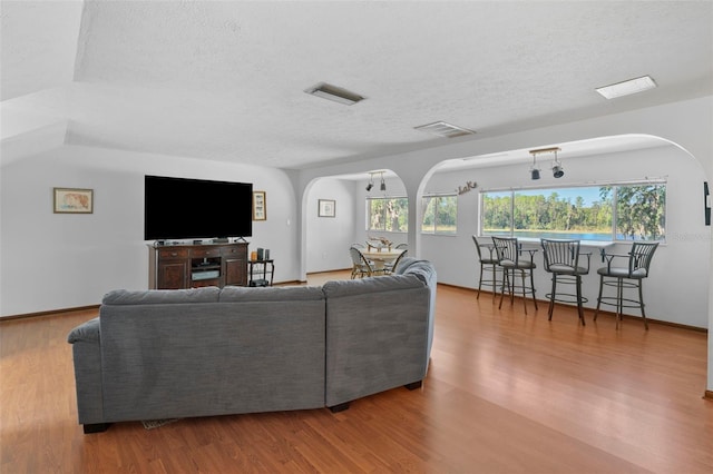 19254 Blount Rd, Lutz, FL 33558 - living room with arched walkways, a textured ceiling, wood finished floors, and baseboards