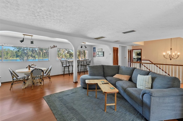 19254 Blount Rd, Lutz, FL 33558 - living room with wood finished floors, a chandelier, arched walkways, and a textured ceiling