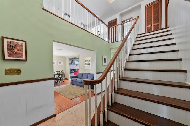 19254 Blount Rd, Lutz, FL 33558 - stairs featuring tile patterned flooring, wainscoting, and a towering ceiling
