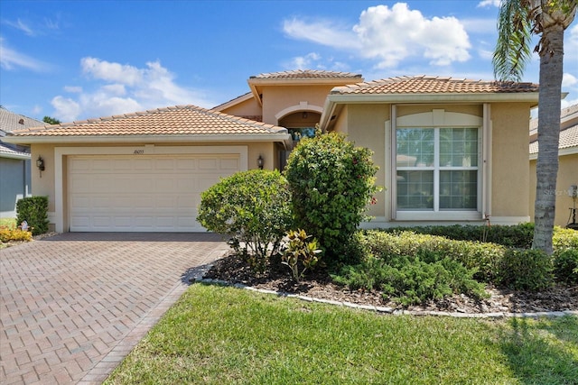 16055 Golden Lakes Dr, Wimauma, FL 33598 - mediterranean / spanish house with stucco siding, an attached garage, decorative driveway, and a tile roof
