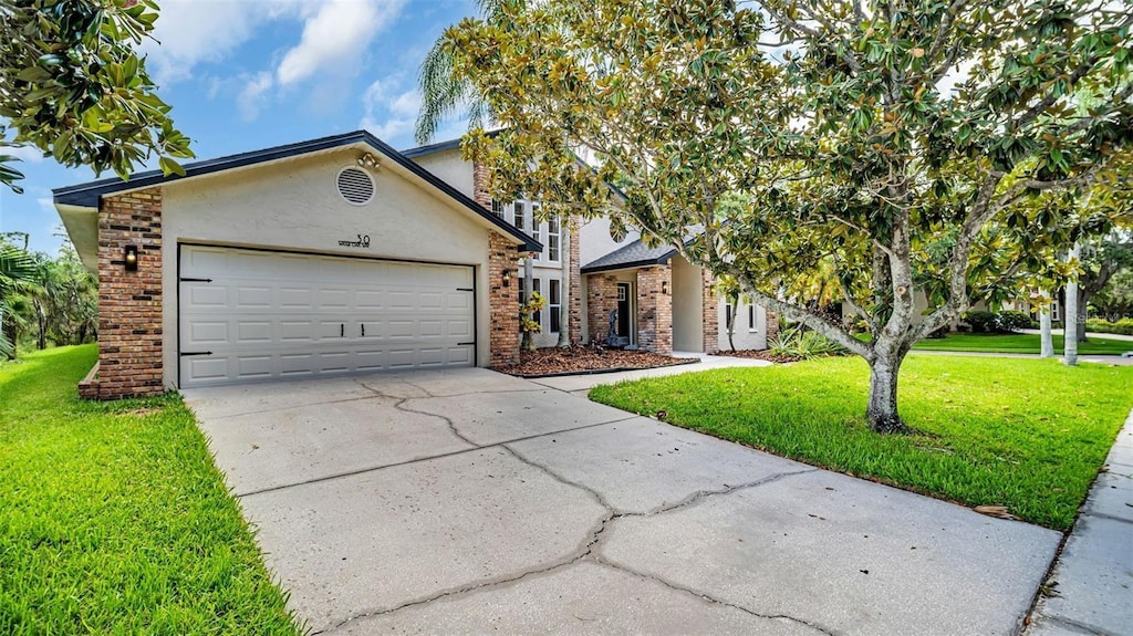 view of front facade featuring stucco siding, an attached garage, concrete driveway, brick siding, and a front yard