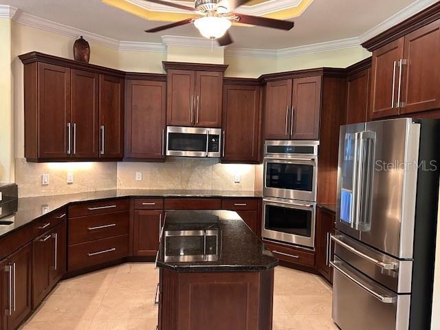 17127 Brown Rd, Odessa, FL 33556 - kitchen featuring stainless steel appliances, a ceiling fan, a center island, dark stone counters, and crown molding