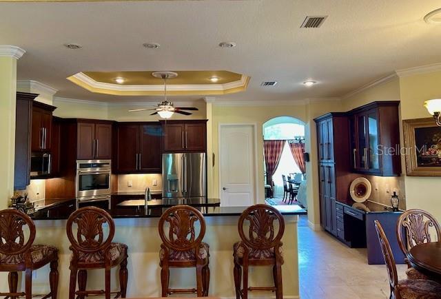 17127 Brown Rd, Odessa, FL 33556 - kitchen featuring stainless steel appliances, a peninsula, a breakfast bar area, ceiling fan, and crown molding